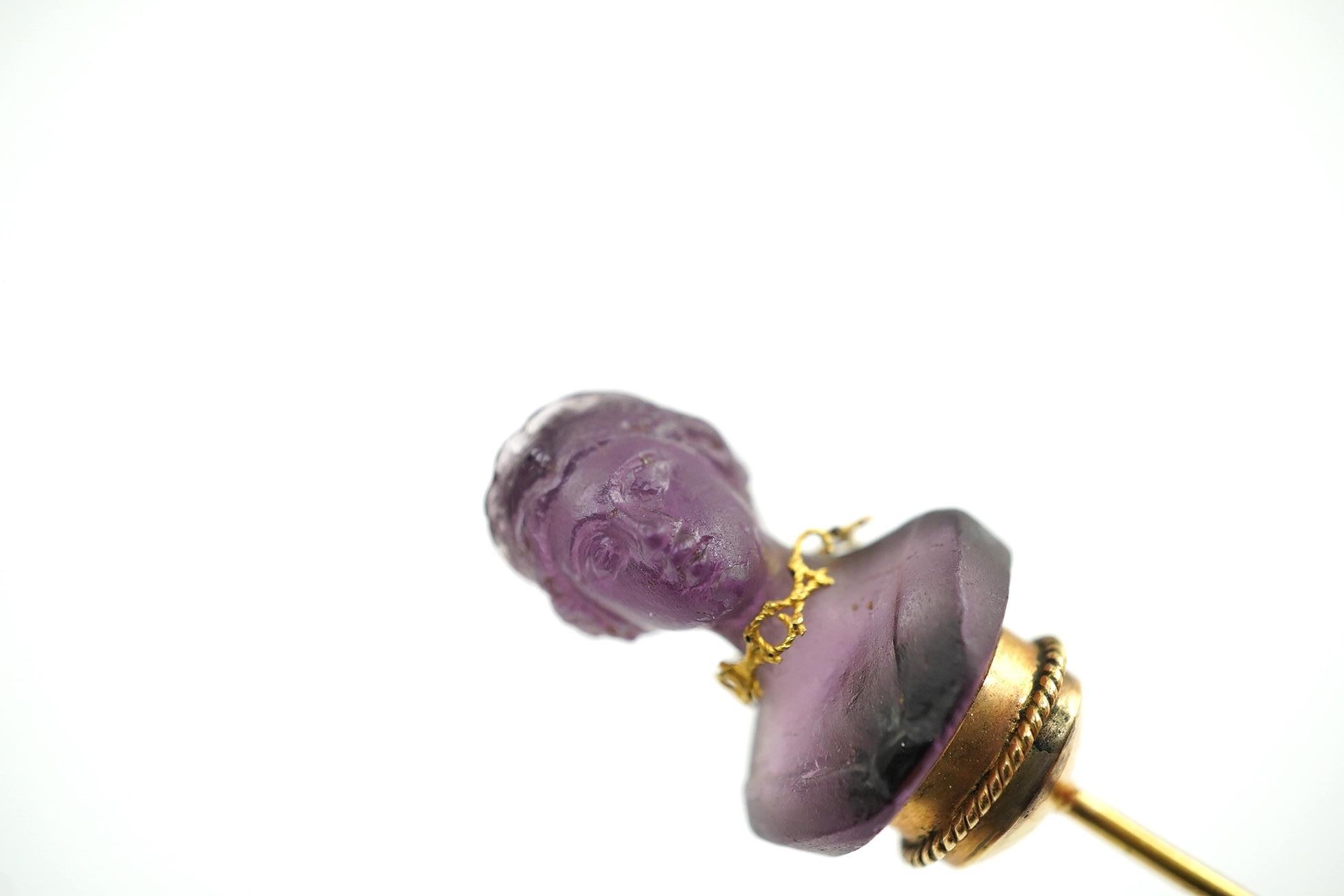 A 19th century French? gold and amethyst set stick pin, the stone carved as the bust of a lady, wearing a necklace